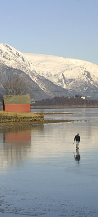 Ice-covered lake, glacier above, and a lone skater